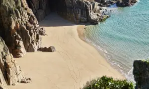 Puste plaże w Anglii, skaliste klify i turkusowa woda. Ślady stóp na piasku prowadzą do ukrytej zatoczki.