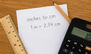 Notatka z kalkulatorem i linijką wyjaśnia, że cal to angielska jednostka długości równa 2,54 cm.