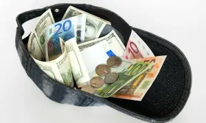 Dolarów i euro w czapce, jakby to był cały majątek z zagranicznego konta bankowego.
