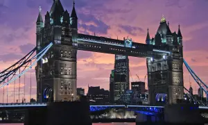 Wieczorny widok na Tower Bridge, jeden z najpiękniejszych zabytków w Londynie, z fioletowym niebem w tle.