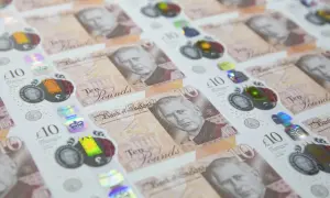 Nowe funty brytyjskie banknoty z wizerunkiem króla Karola III, w tle widać poprzednie banknoty z królową Elżbietą II.