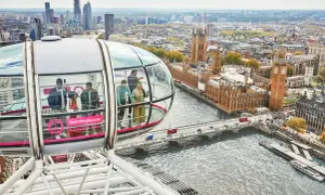 Ludzie podziwiają panoramę Londynu z kapsuły diabelskiego młyna. Widać Tamizę, Parlament i Big Bena.