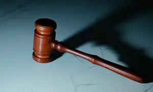 Drewniany młotek sędziowski na marmurowym blacie. Symbolizuje sprawiedliwość i prawa pracownika, w tym 5 praw pracownika.
