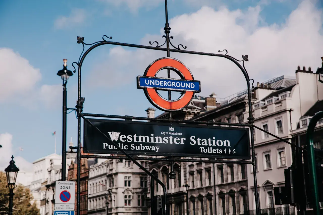 Znak Westminster Station, ikona metra londyn ceny. Klasyczny okrągły symbol "Underground" nad tablicą z nazwą stacji i informacją o toaletach.