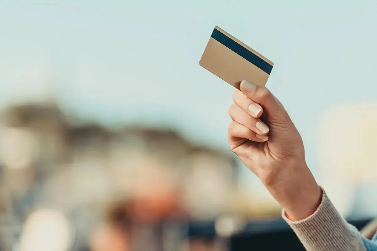 Dłoń trzyma złotą kartę Mastercard debit fx.