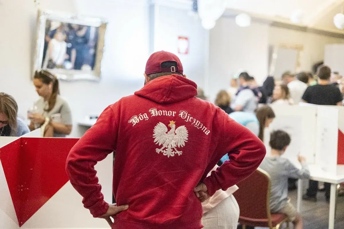 Polacy w UK. Mężczyzna w czerwonej bluzie z orłem i napisem "Bóg Honor Ojczyzna" stoi w tłumie.