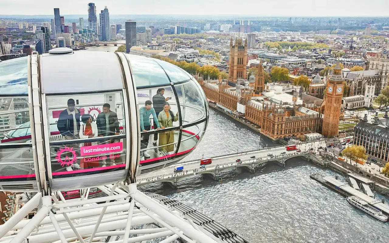 Ludzie podziwiają panoramę Londynu z kapsuły diabelskiego młyna. Widać Tamizę, Parlament i Big Bena.