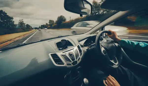 Widok z samochodu podczas jazdy po Polsce. Na desce rozdzielczej widoczny uchwyt na telefon. W tle droga i inne pojazdy. Dowód V5C rejestracja w Polsce.