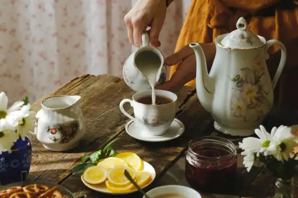 Chwila relaksu przy herbacie, tak o której Anglicy piją herbatę. Mleko wlewane do filiżanki, obok dzbanek, cytryny i dżem.