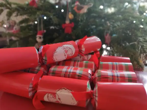 Boże Narodzenie w Wielkiej Brytanii tradycje: czerwone świąteczne petardy z Mikołajem i w kratkę, w tle choinka.